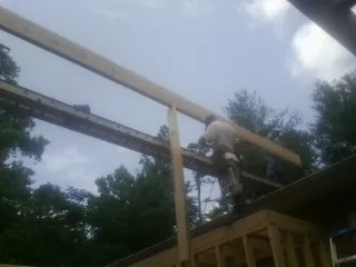 Carpenter setting a ridge beam over a new addition frame — Ice Dam Removal by Roofing Brothers in Henrietta